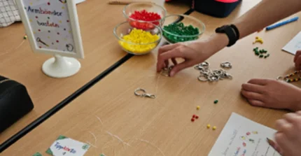 Mathematikmaterialien und Schreibsachen auf einem Tisch, Kinderhände, die damit arbeiten