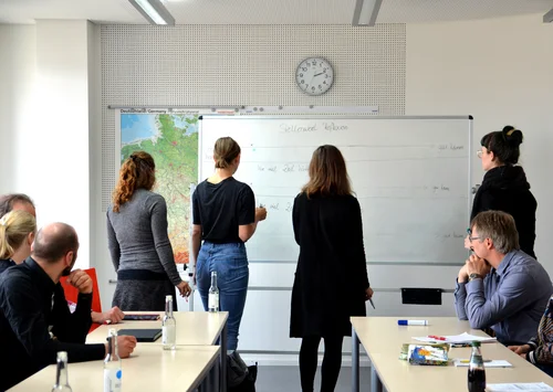 Teilnehmende eines Workshops stehen am Whiteboard