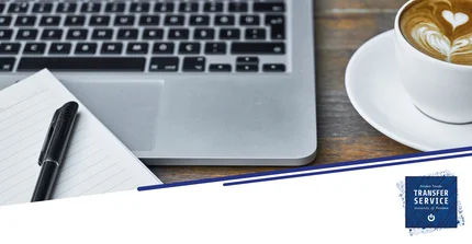 Laptoptastatur auf Tisch mit Block und einer Tasse Kaffee