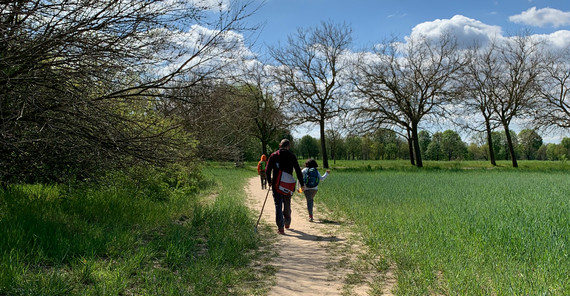 Mann mit zwei Kindern auf einem Weg neben einem Feld. Foto: Aura Cárdenas